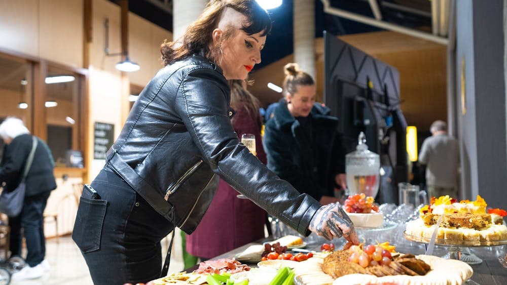 Two women picking up food of a table-full of food