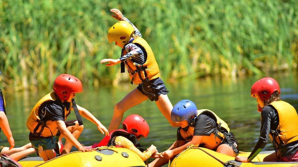 A camper leaps from one white water raft to another