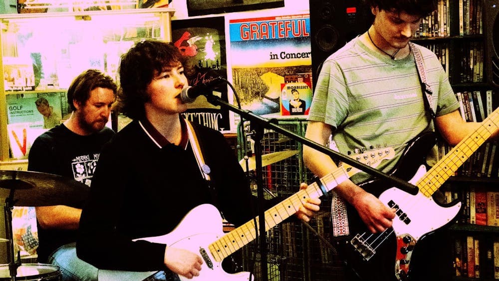 Pullover Band performing, playing inside behind a wall covered in band posters