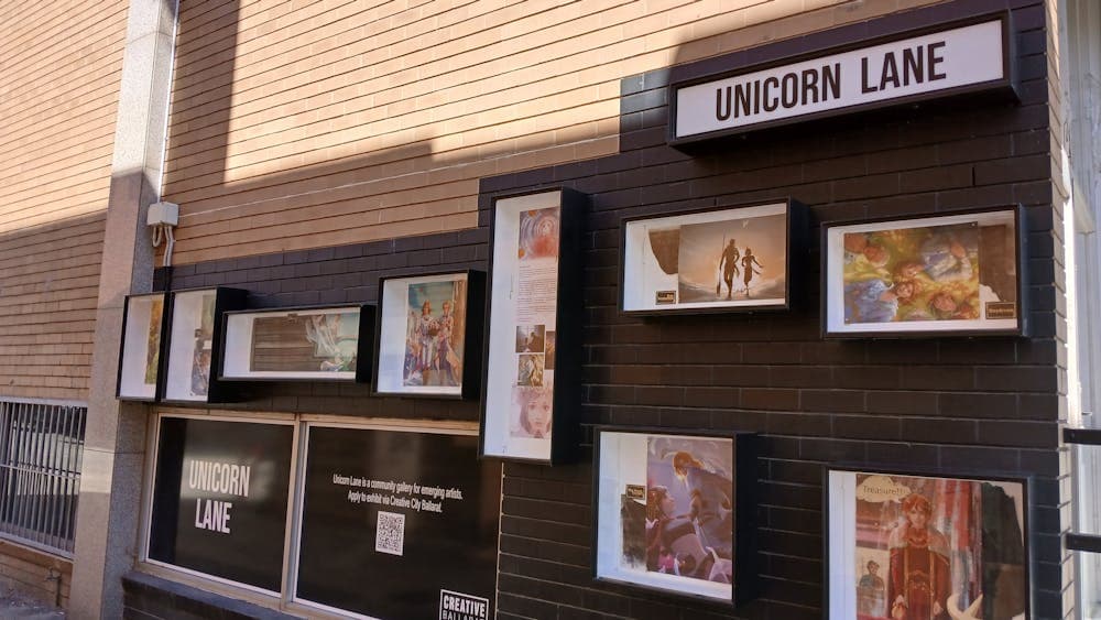 Outdoor display boxes with digital artworks installed on a black and orange brick wall.