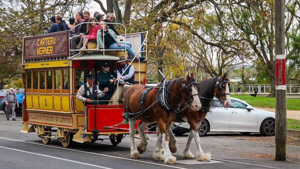 Old double deck tram pulled by two large horses.