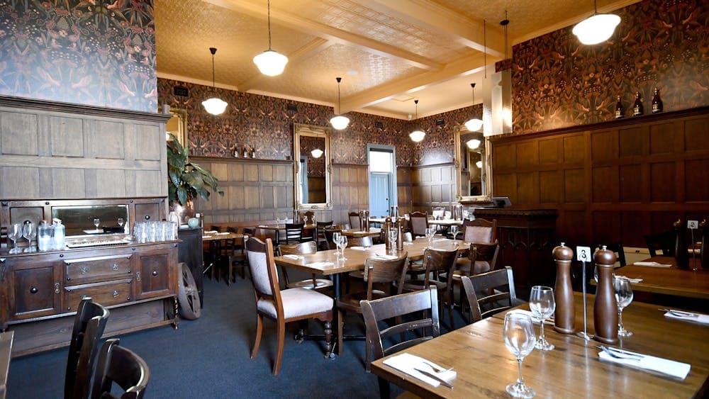 Market hotel dining room. Oak panel lined room with carpet and wooden chairs and tables.