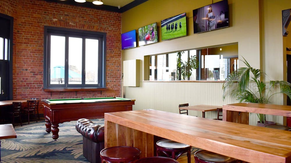 Alternative view of the Sports bar. Wooden table, bar stools, and pool table.