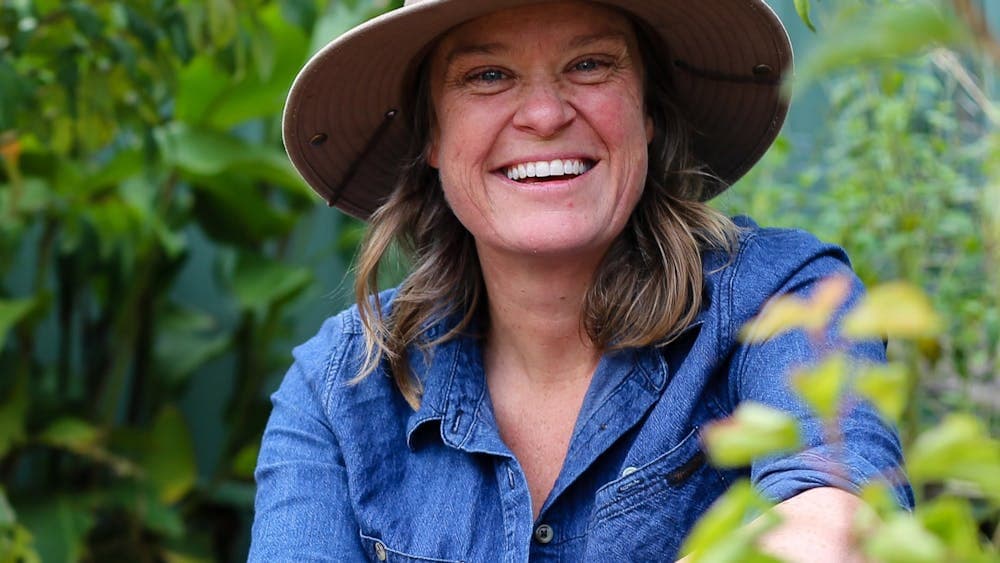 Millie Ross is smiling and wearing a blue button up shirt and a brown broad brim hat