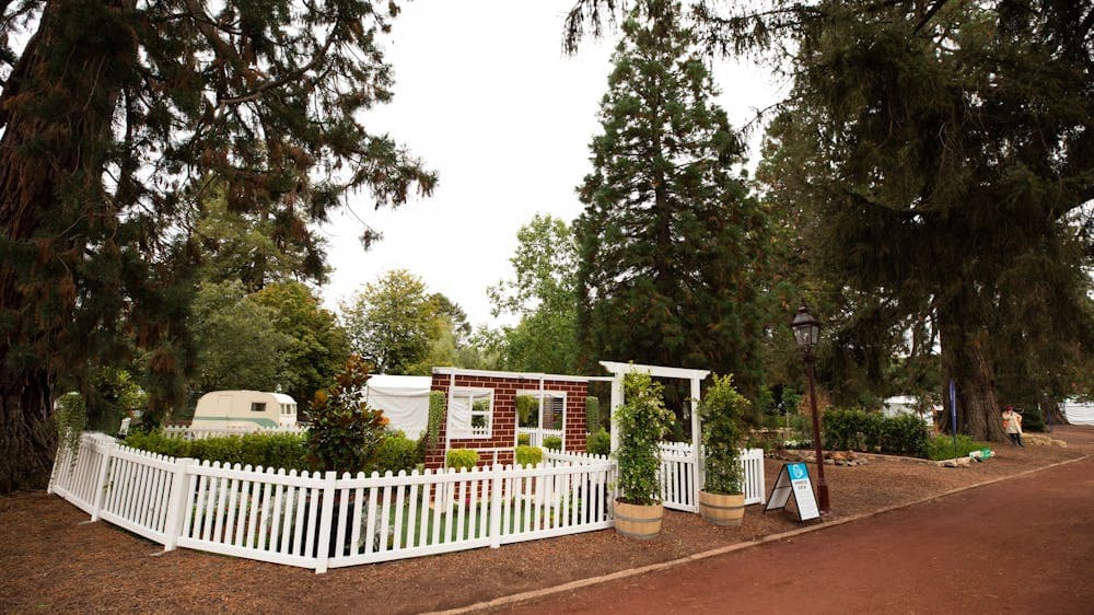 A little garden is set up behind a white picket fence along a path of the Ballarat Botanical Gardens