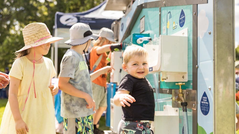 A group of children stand at taps, playing with the water