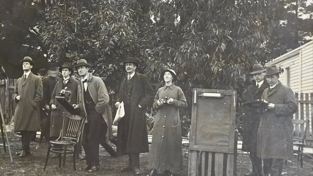 A man and a woman in century old clothing looking up at the sky.