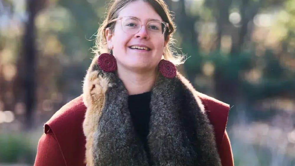 Shannen Mennen wearing red top and a possum skin cloak over her shoulders