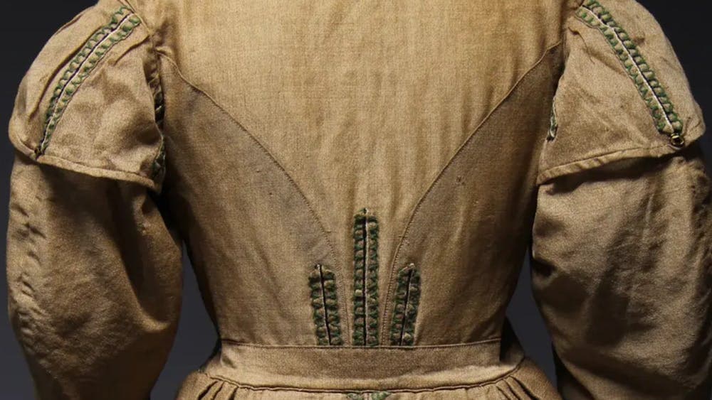 Back of 19th century light brown dress with green trimming and wide sleeves