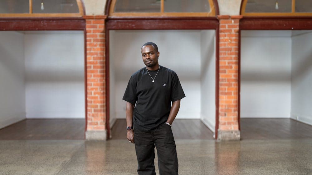 Campbell Addy, British-Ghanaian man wearing black t-shirt and jeans standing in heritage building