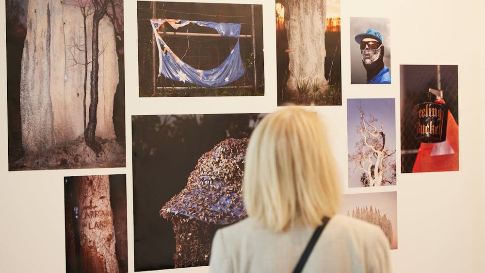 A woman with blond hair looks at a photography exhibition