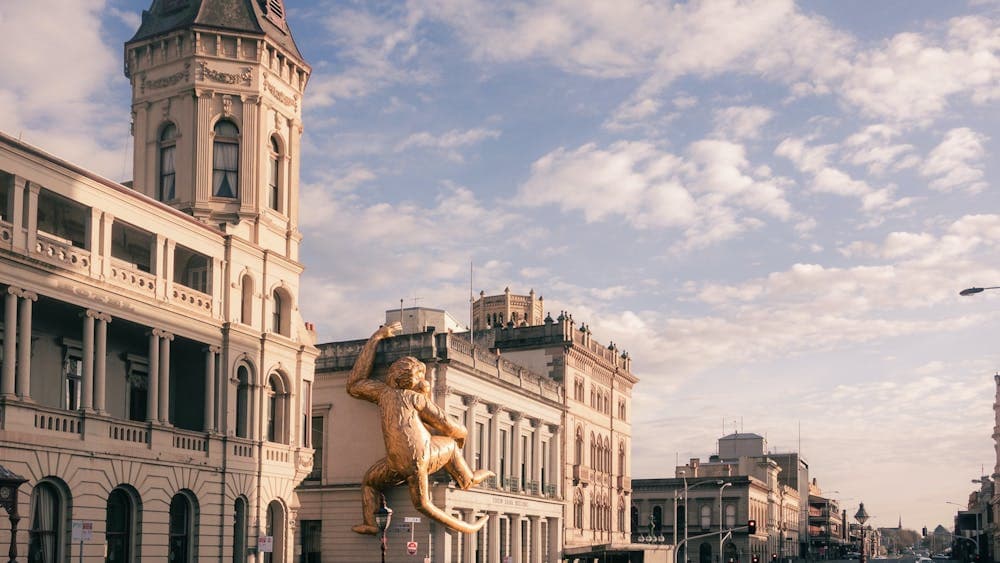 A Victorian heritage streetscape and a giant gold monkey clings to the side of a building