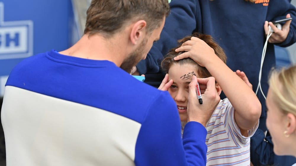 A football player signing a child's forehead.