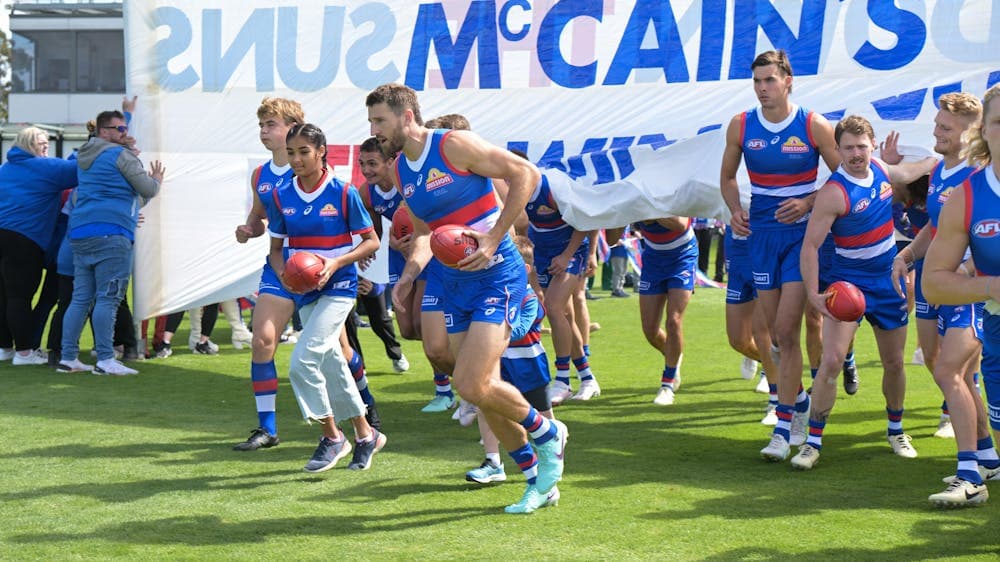 Football players running through the banner