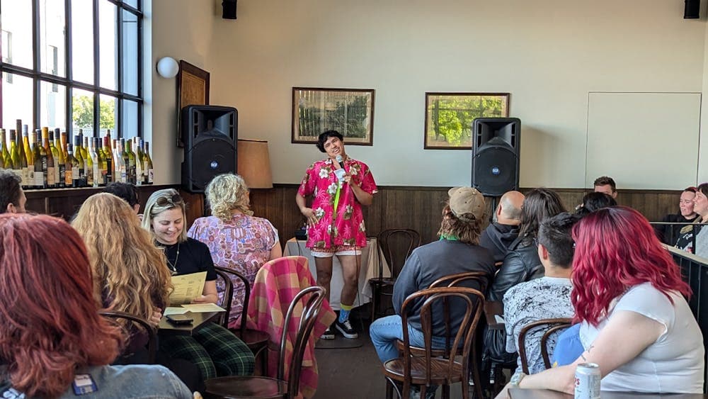 Host, Neptune Henriksen, performing in at Goodwill Comedy Club, in a pink and yellow outfit