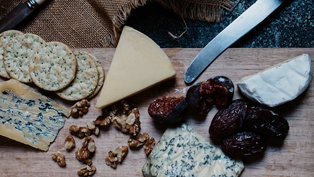 a cheese plate with grapes and a knife