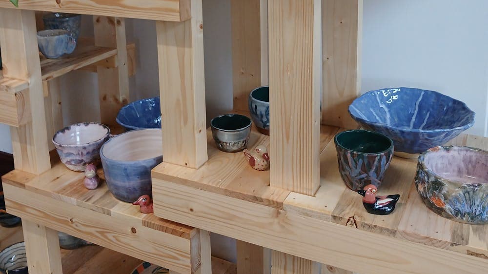 Ceramic bowls, mugs and bird sculpture on a wooden display