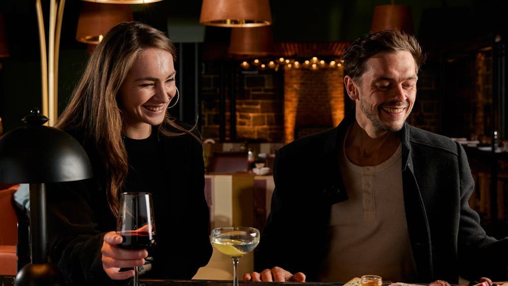 Customers seated at the bar enjoying drinks and food