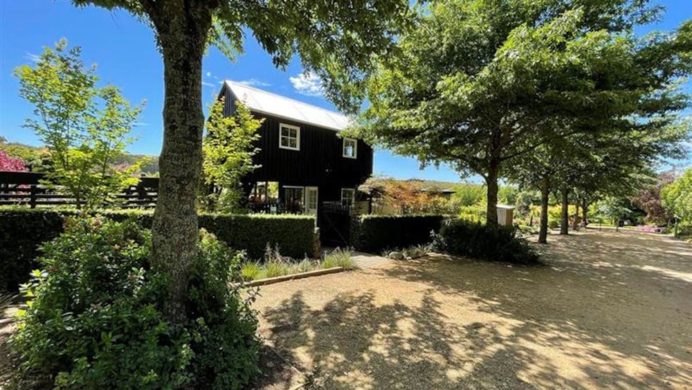 Bluestone double story house with trees surrounding and blue sky