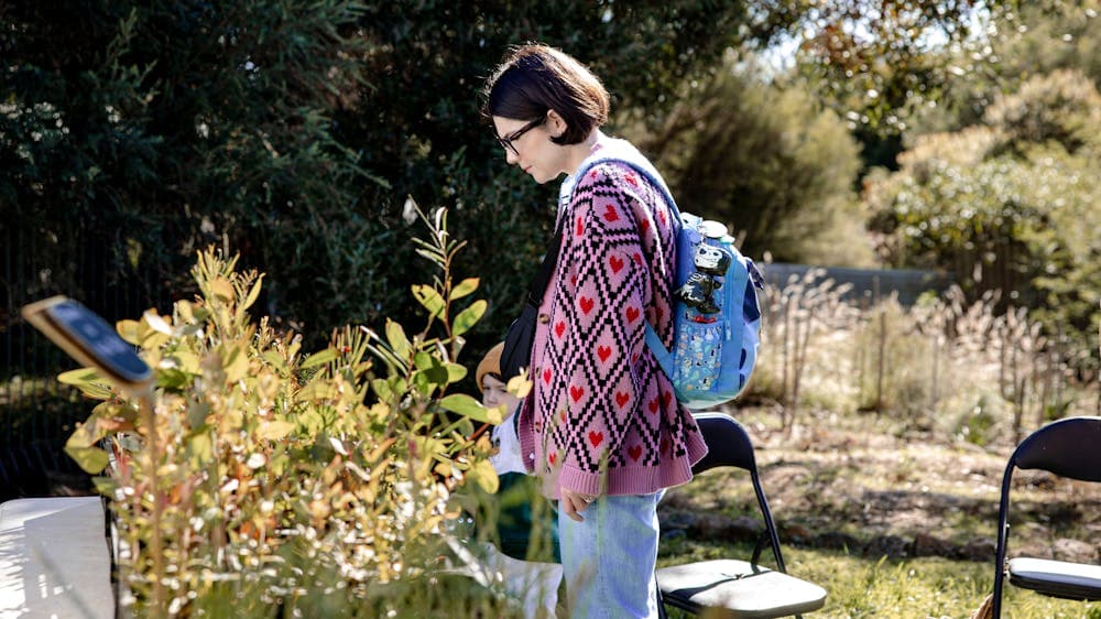 The woman wears a colourful jumper patterned with love hearts within diamonds