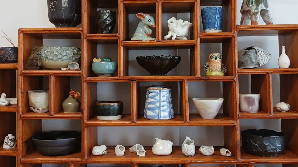 Small wooden shelf filled with a display of different ceramic works.