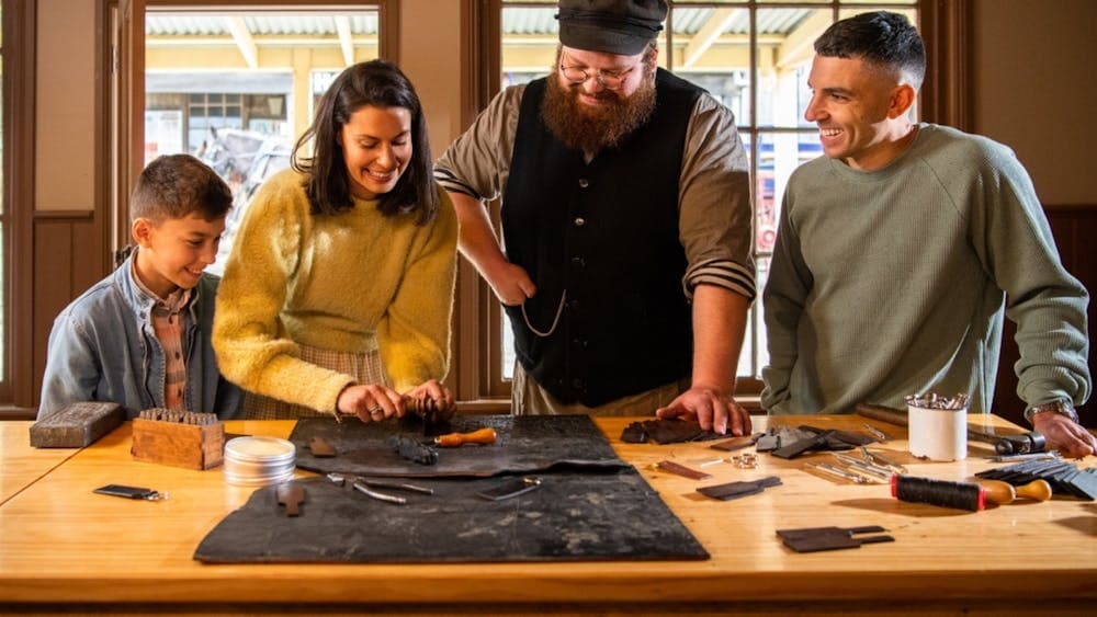 Family making keyring with Sovereign Hill leather-maker inside workshop