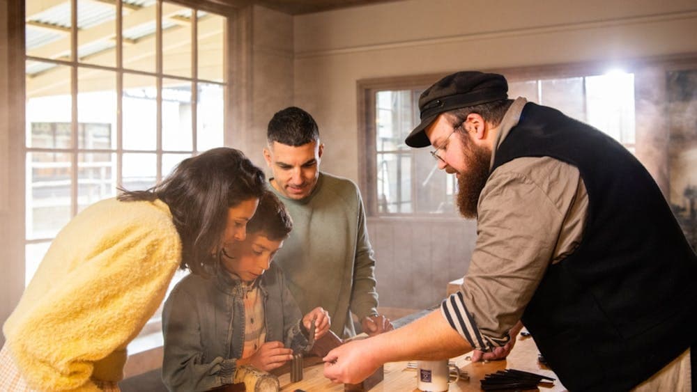 Family making keyring with Sovereign Hill leather-maker inside workshop