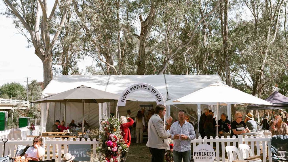 People attending the Pyrenees Unearthed Festival standing outside a white VIP tent