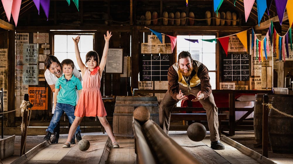 Boy and girl bowling with man in 19th century costume