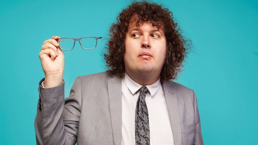 Ray O'Leary in a grey suit holding his spectacles